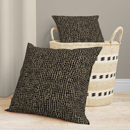 Chocolate solid fabric throw pillows; one propped in a woven basket, another on a light wood floor.
