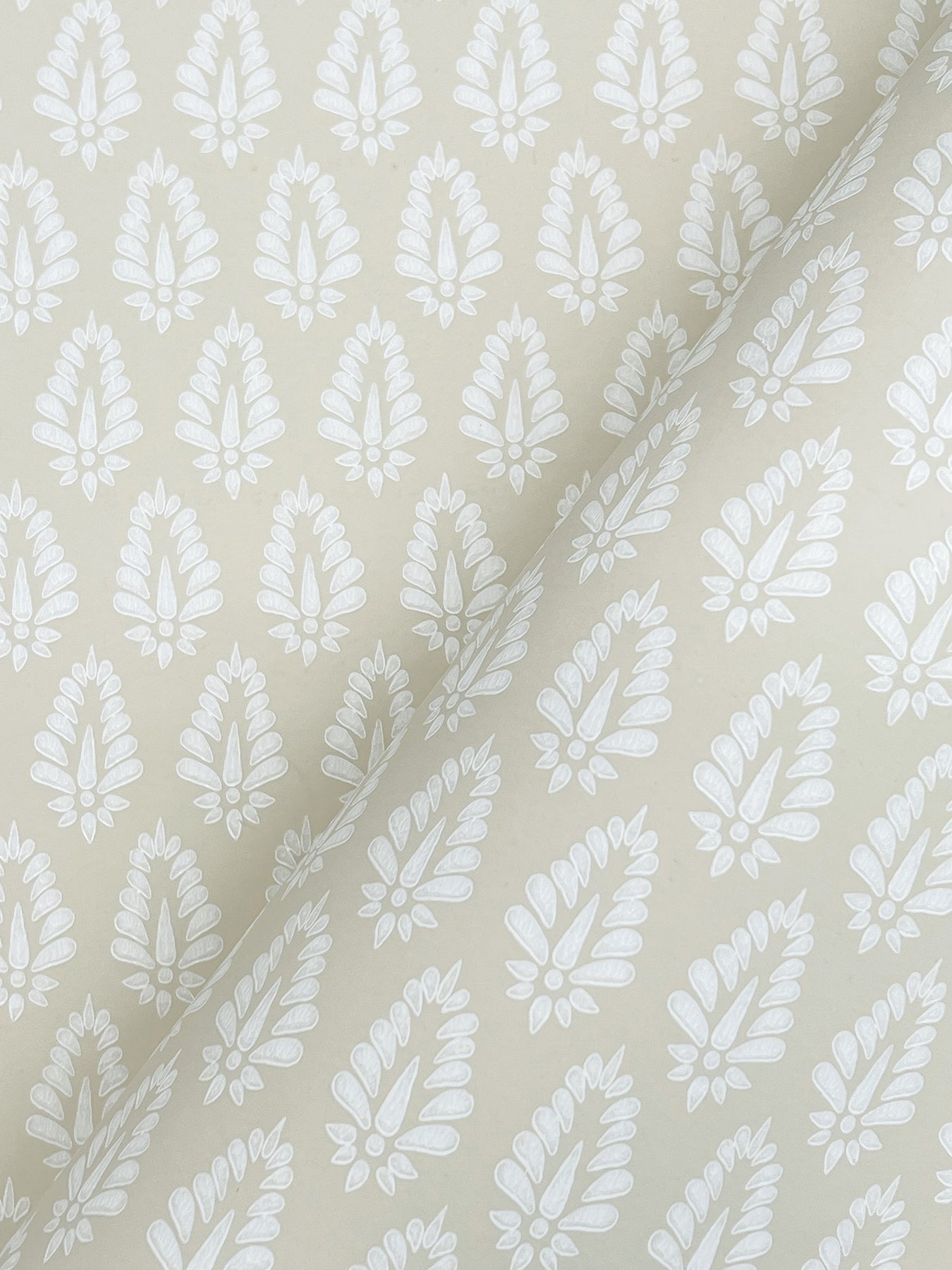 Beige wallpaper close-up showing a white leaf/feather repeating small-print pattern.