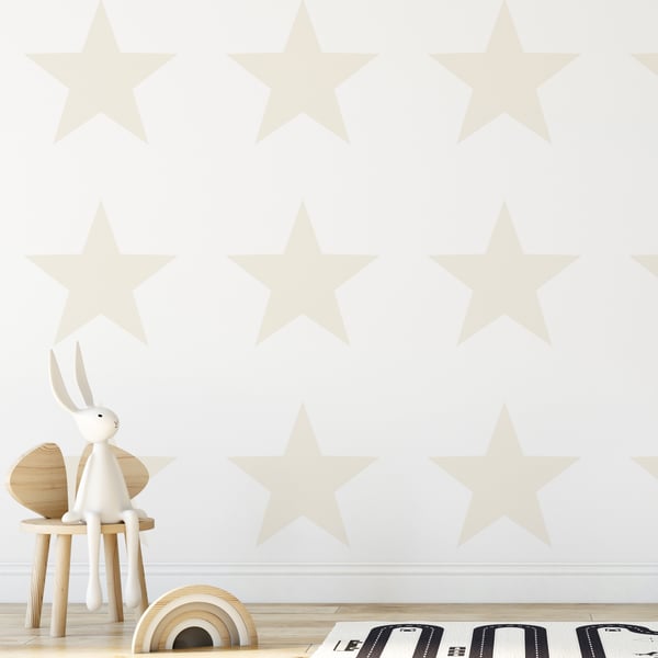 White wooden bunny on a light wood stool with natural ears; pale star wallpaper and a wooden rainbow toy on the floor.