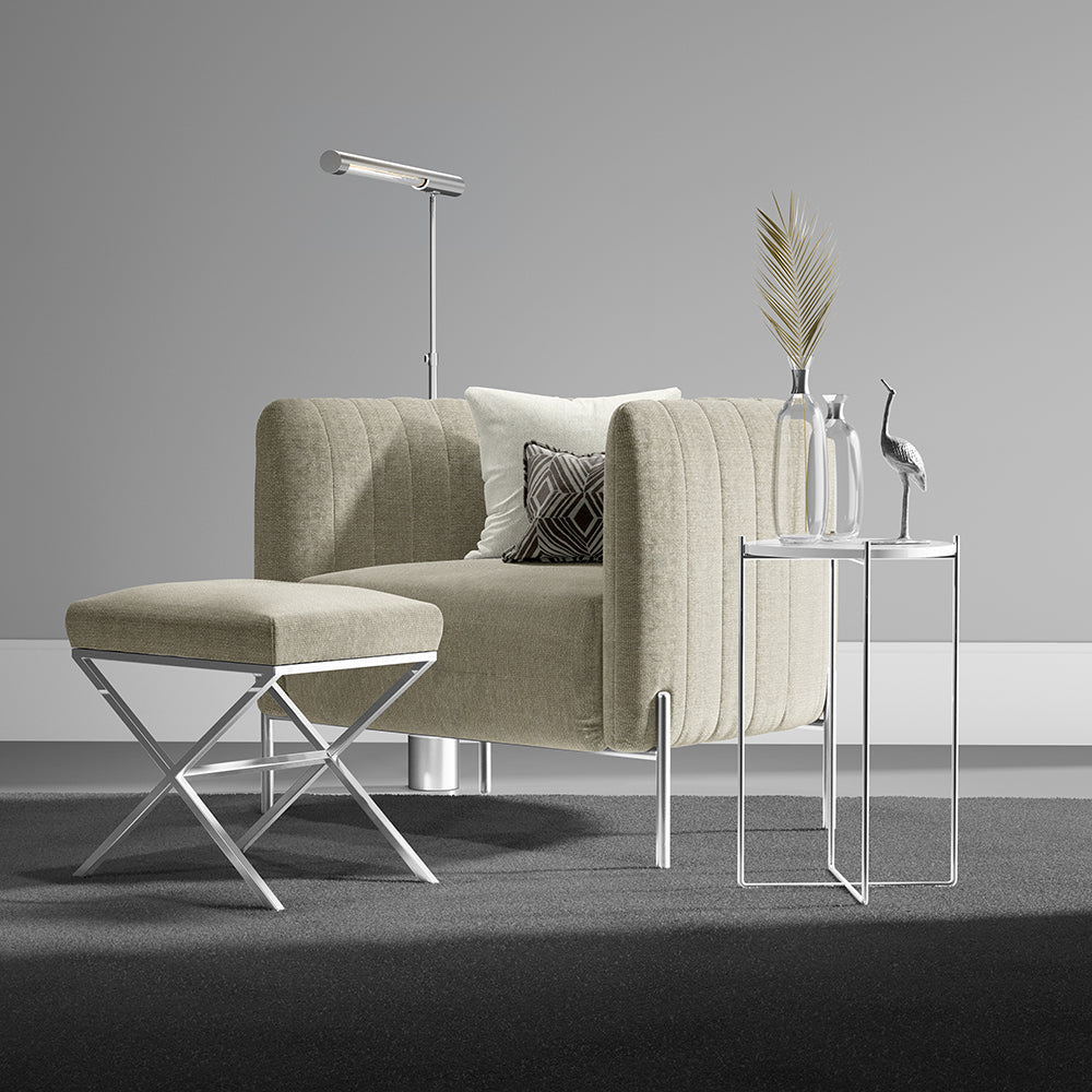 Oatmeal solid fabric upholstery; modern living room scene featuring a beige tufted sofa & matching ottoman, chrome legs, and a glass side table with vases.