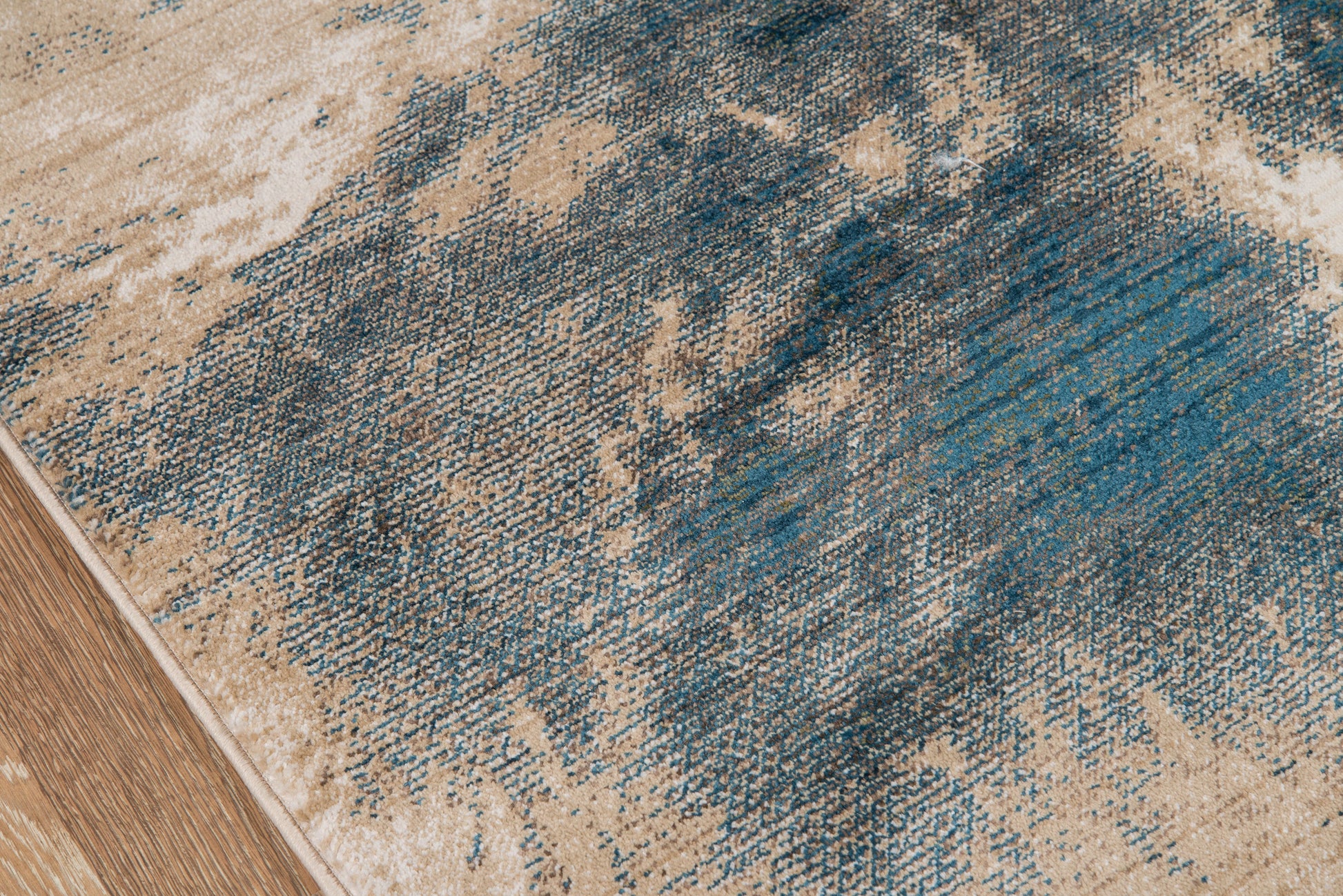 Blue and beige abstract rug with distressed brush-stroke pattern on wooden floor.