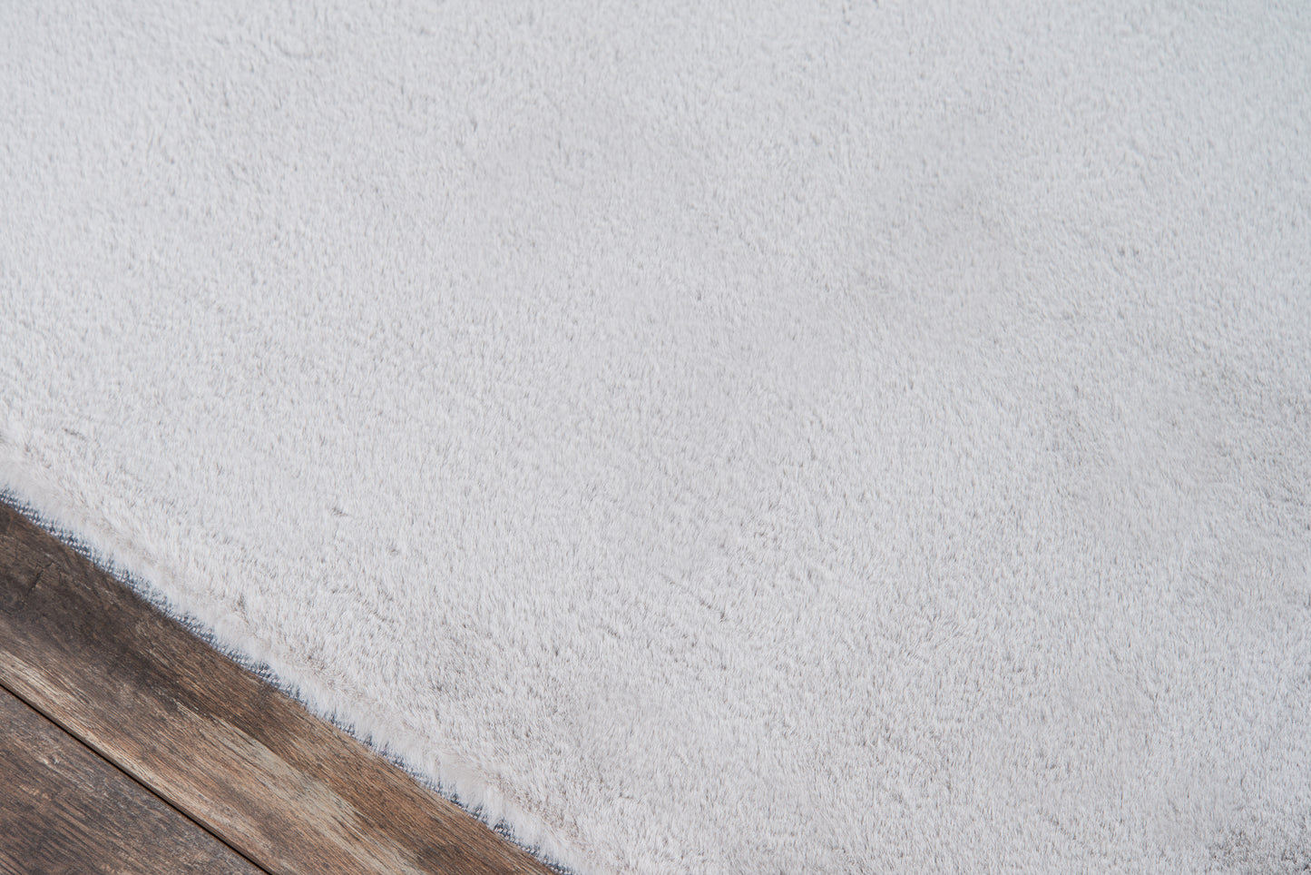 Soft light-gray shag area rug, 5' x 7', with subtle texture on dark wood flooring.