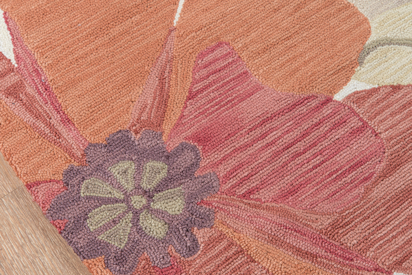 Shaggy floral area rug in warm orange and coral with lavender-purple center flower and green petals; loop pile.