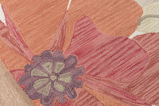 Shaggy floral area rug in warm orange and coral with lavender-purple center flower and green petals; loop pile.