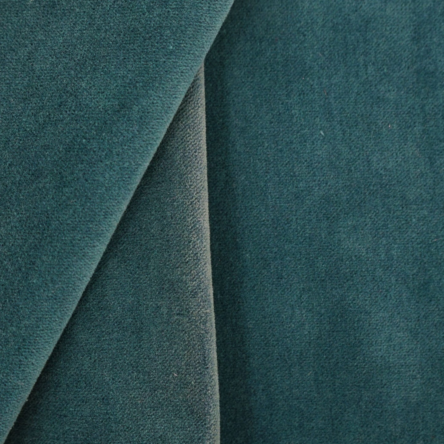 Blue velvet upholstery close-up with curved seam; plush fabric for sofa or cushion.
