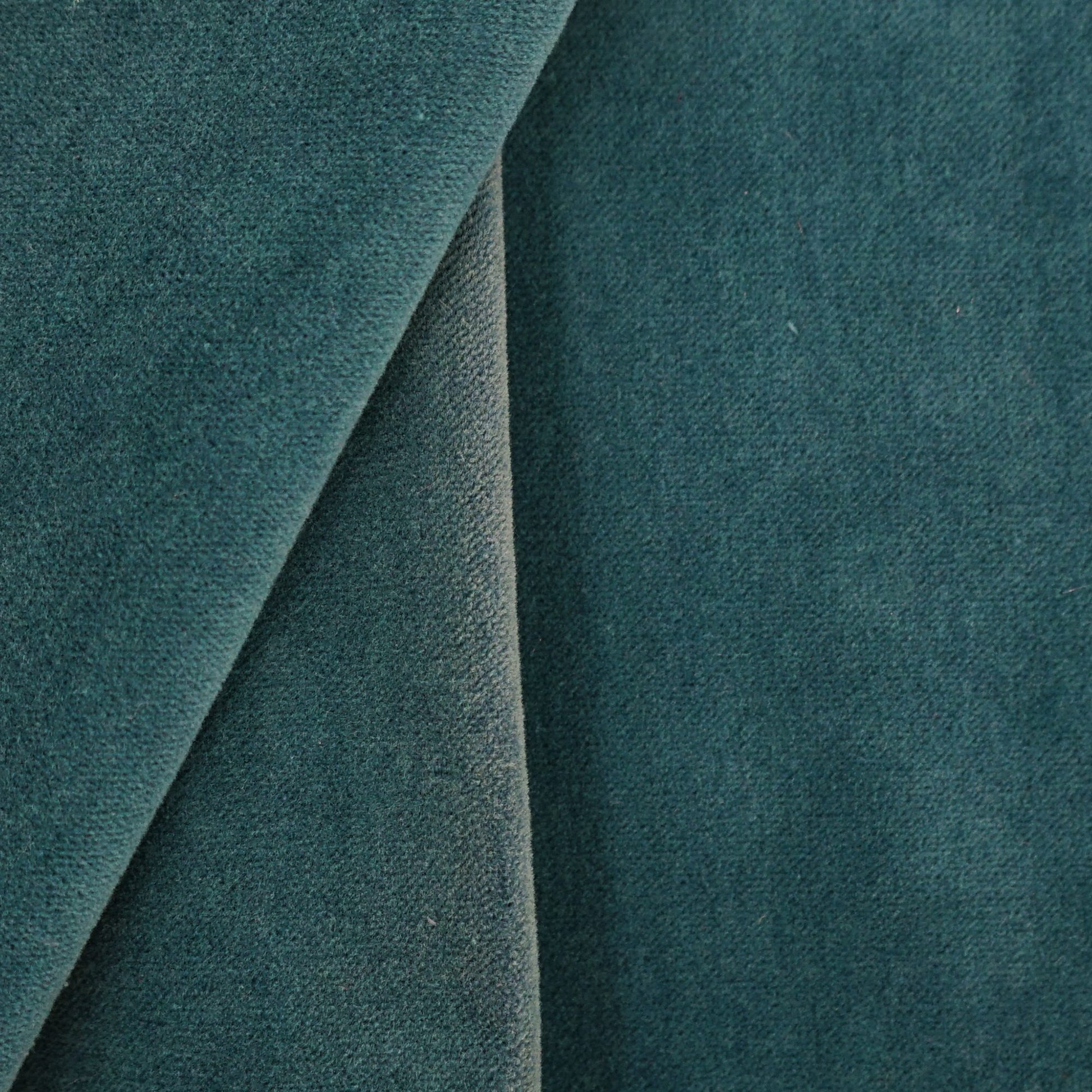 Blue velvet upholstery close-up with curved seam; plush fabric for sofa or cushion.