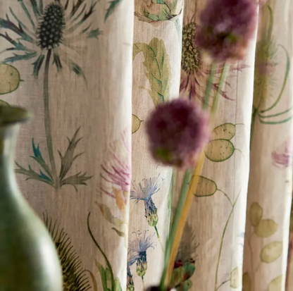 Close‑up of Sanderson Thistle Garden linen fabric (DEBB226423) showing printed thistle and seed‑pod motifs in soft fig tones and natural linen background — ideal for upholstery, draperies, cushions and interior design projects.