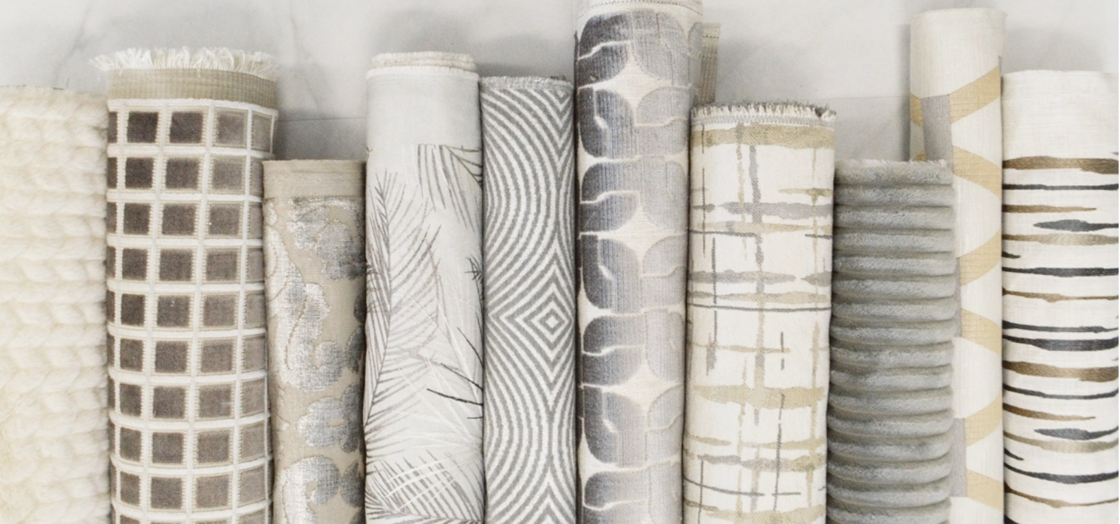 Collection of patterned fabric rolls on a light gray background