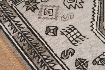 Gray-beige rug with black geometric border and leaf motifs on wood floor.
