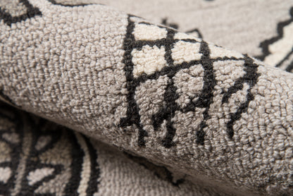 Close-up of a grey textured rug with black geometric lattice pattern and cream accents.