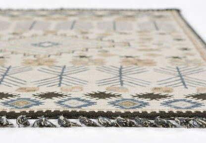 Rectangular woven rug with ivory base, blue and brown geometric diamonds, and fringed edge.