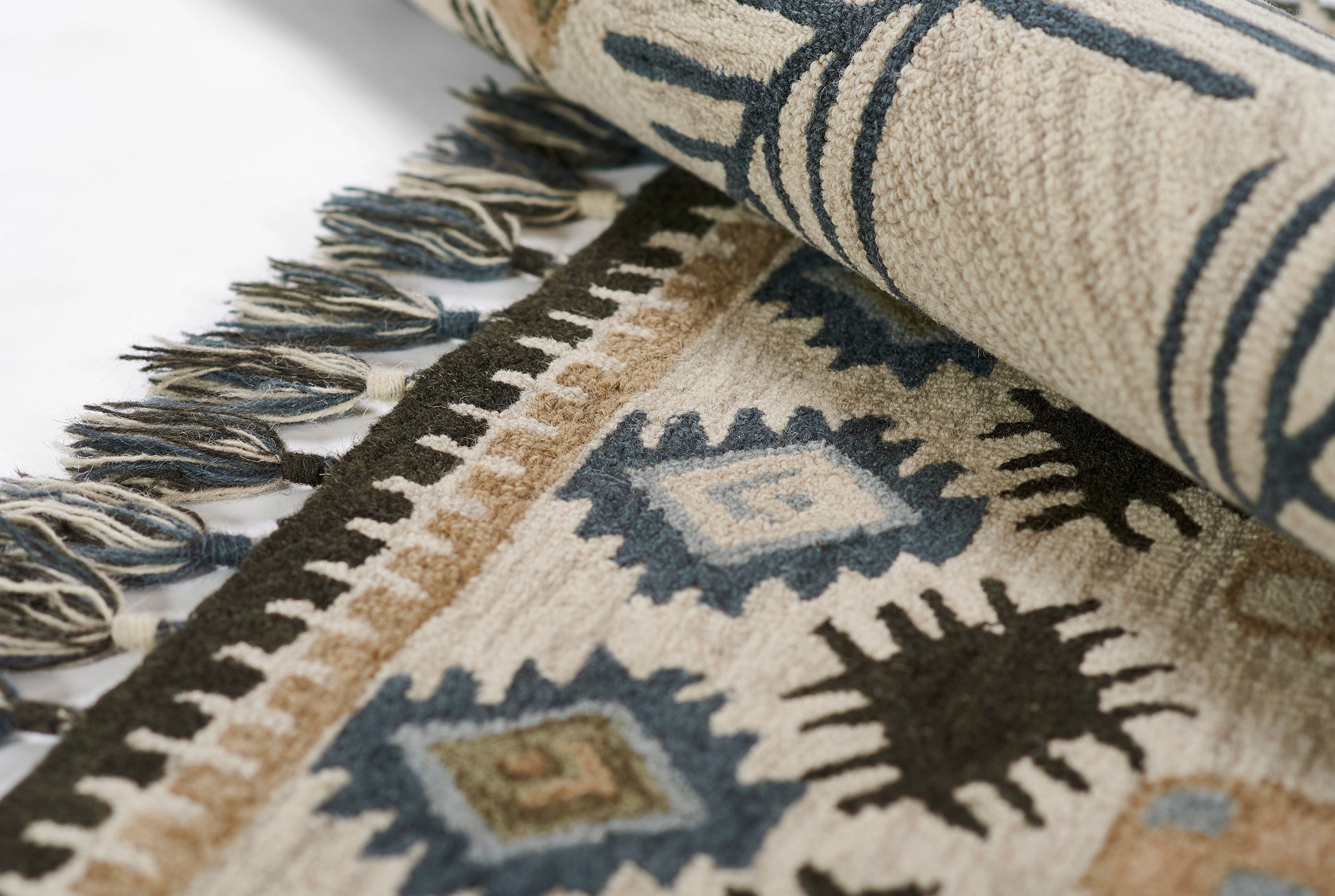 Close-up of a beige kilim runner with blue diamond motifs, brown accents, and fringed edges.