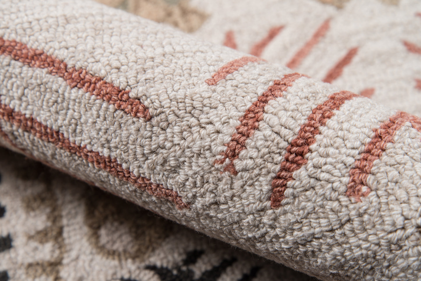 Close-up of a beige loop-pile rug with rust stripes and a subtle geometric pattern.