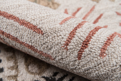 Close-up of a beige loop-pile rug with rust stripes and a subtle geometric pattern.