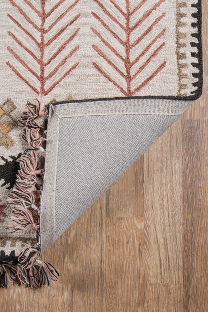 Beige rug with red tree/fern motifs, black border edge, pink tassels; folded corner shows gray underside on wood floor.