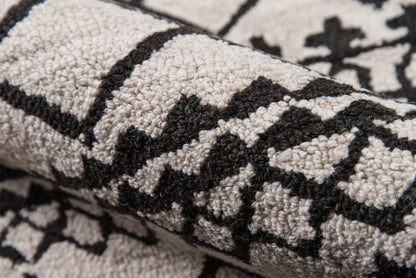 Close-up of a gray textured rug featuring a bold black geometric pattern and plush pile.