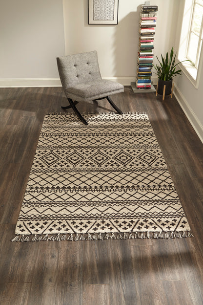 Gray and cream geometric runner rug with fringe edges on dark wood floor beside a gray upholstered lounge chair