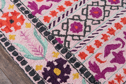 Multicolor pink runner rug with geometric and floral patterns, purple, orange, yellow, teal accents, black border on wood floor, 2' x 8'.