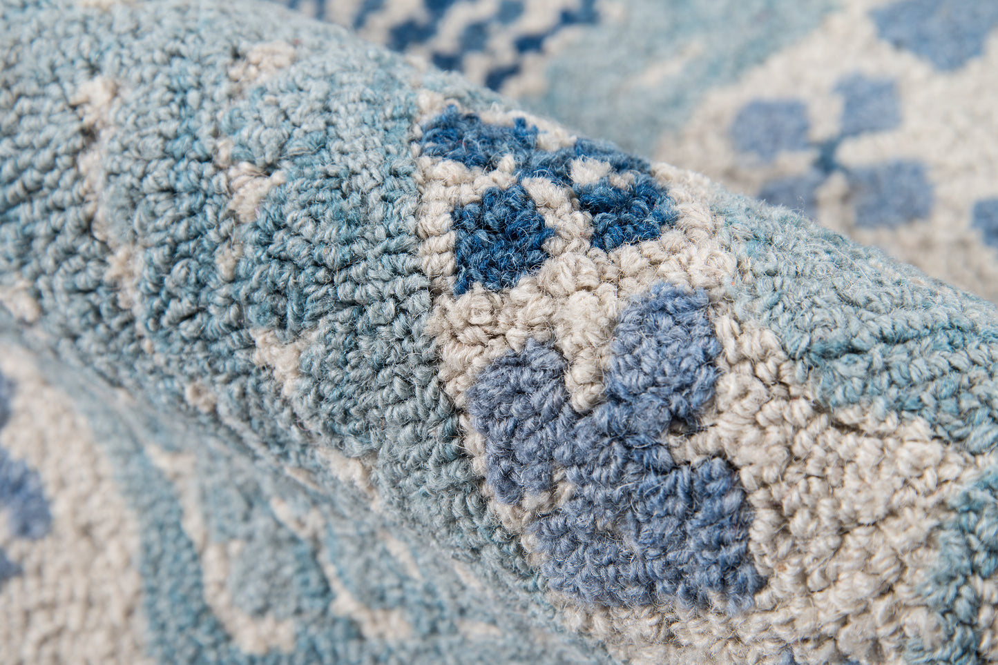 Close-up of blue & white tufted rug with plush pile and geometric diamond pattern.