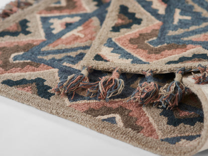 Aztec-inspired geometric rug in beige, navy, pink and brown with fringe tassels.