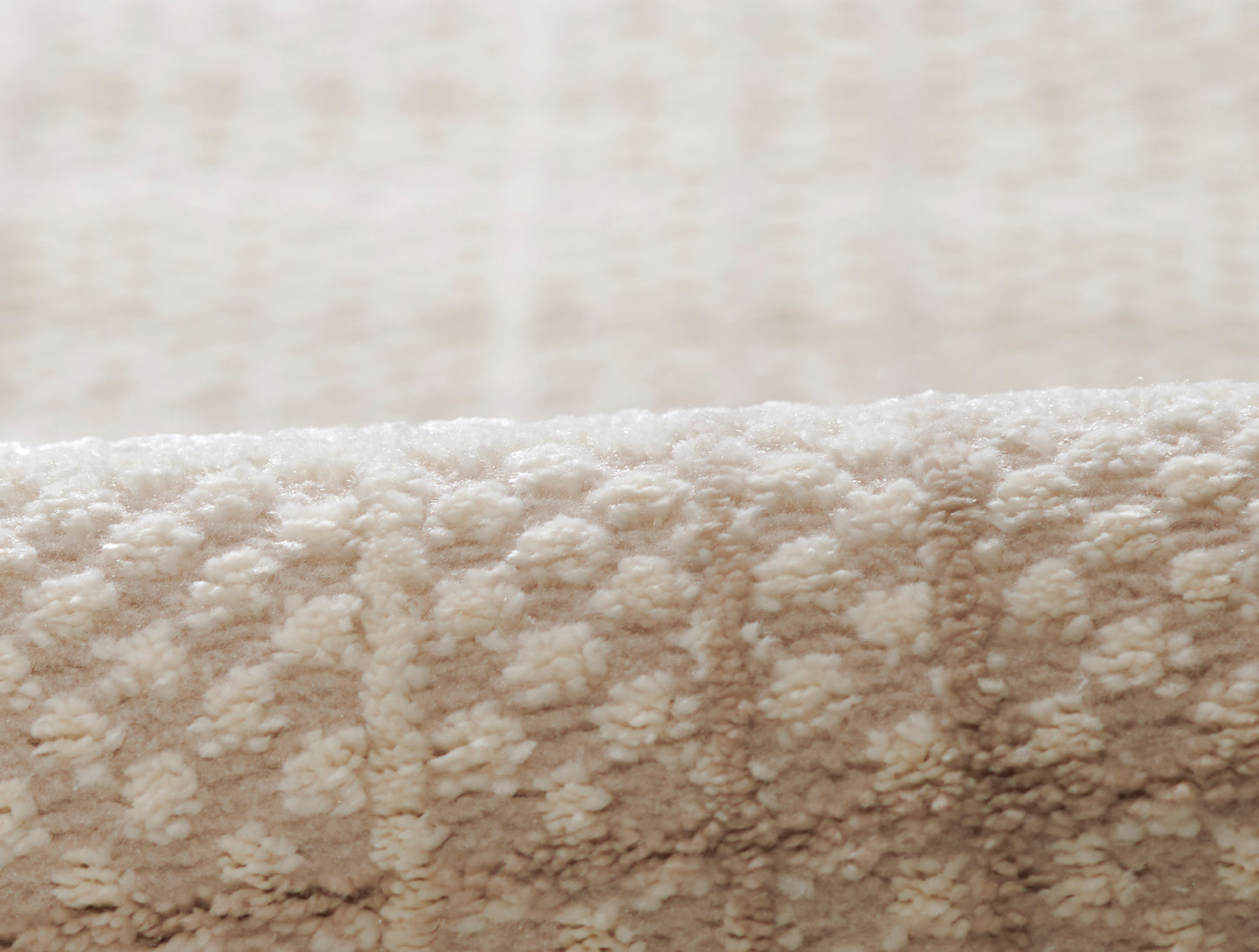 Soft beige plush rug close-up with dense looped pile & cozy textured surface.