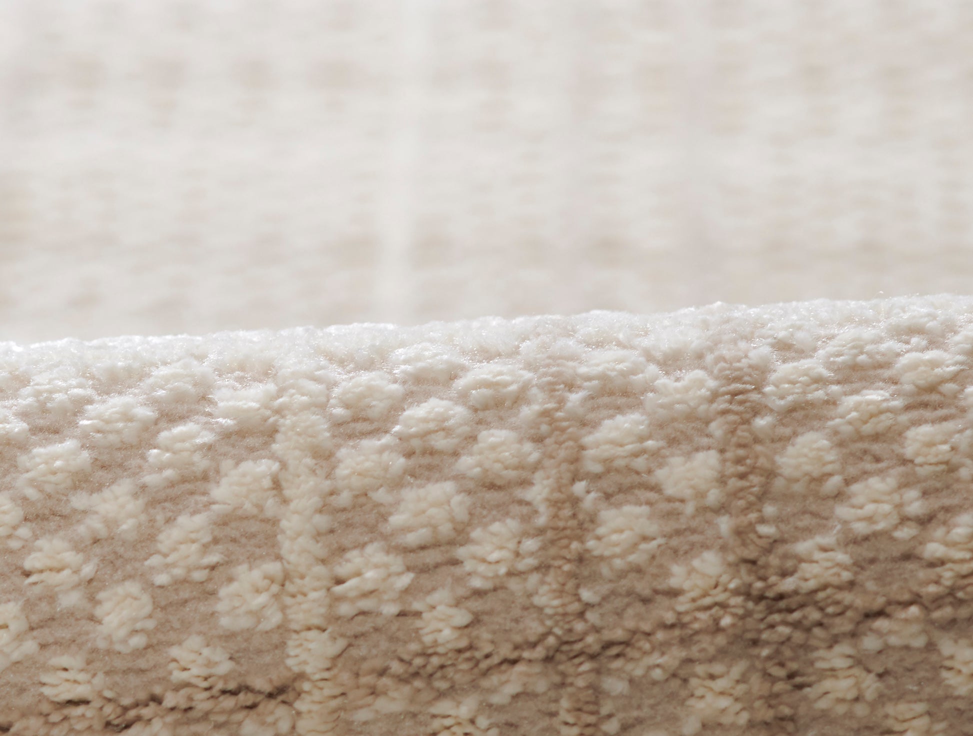 Soft beige plush rug close-up with dense looped pile & cozy textured surface.