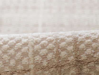 Soft beige plush rug close-up with dense looped pile & cozy textured surface.