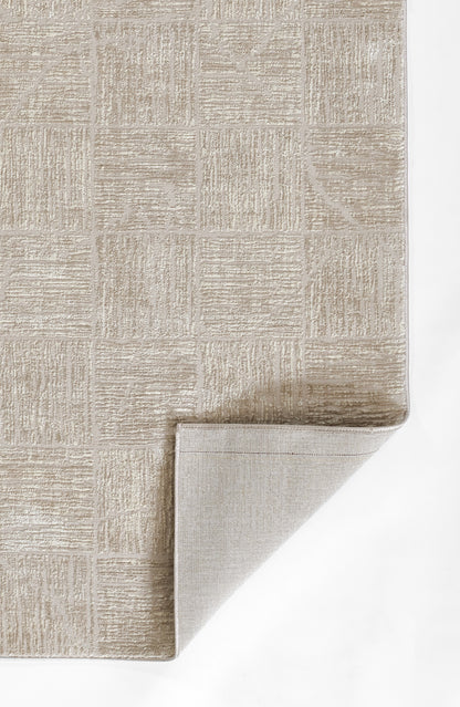 Beige geometric area rug with square block pattern and textured pile; folded corner reveals light tan underside.