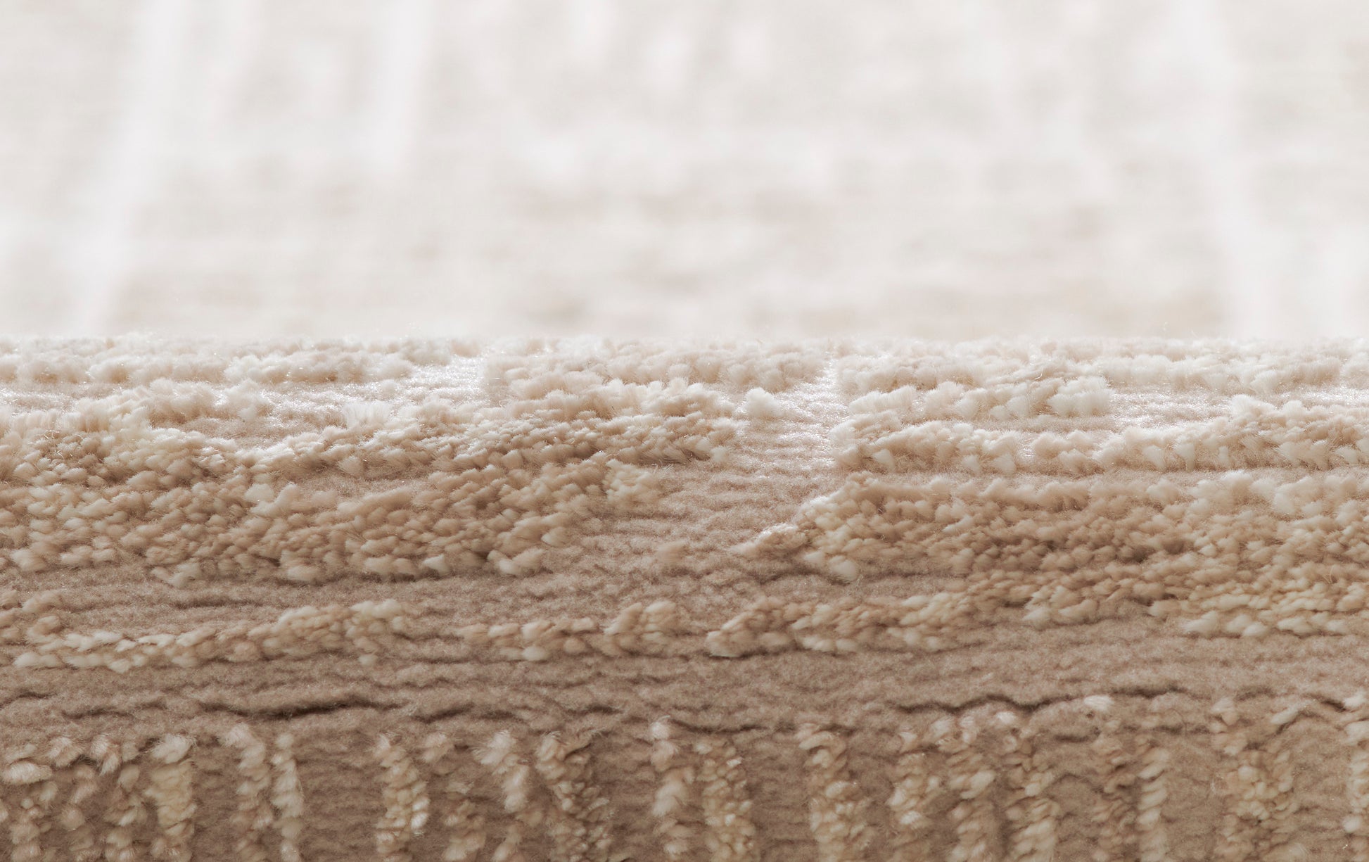 Beige shag rug close-up with thick plush pile in warm neutral tones.