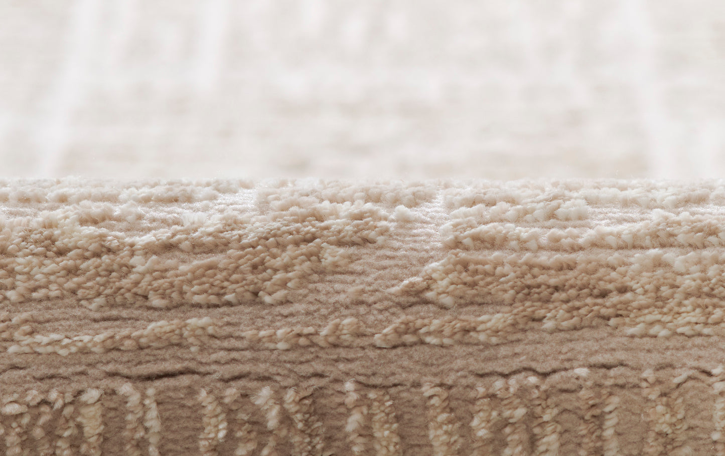 Beige shag rug close-up with cream pile atop a tan base; plush, textured, layered look.