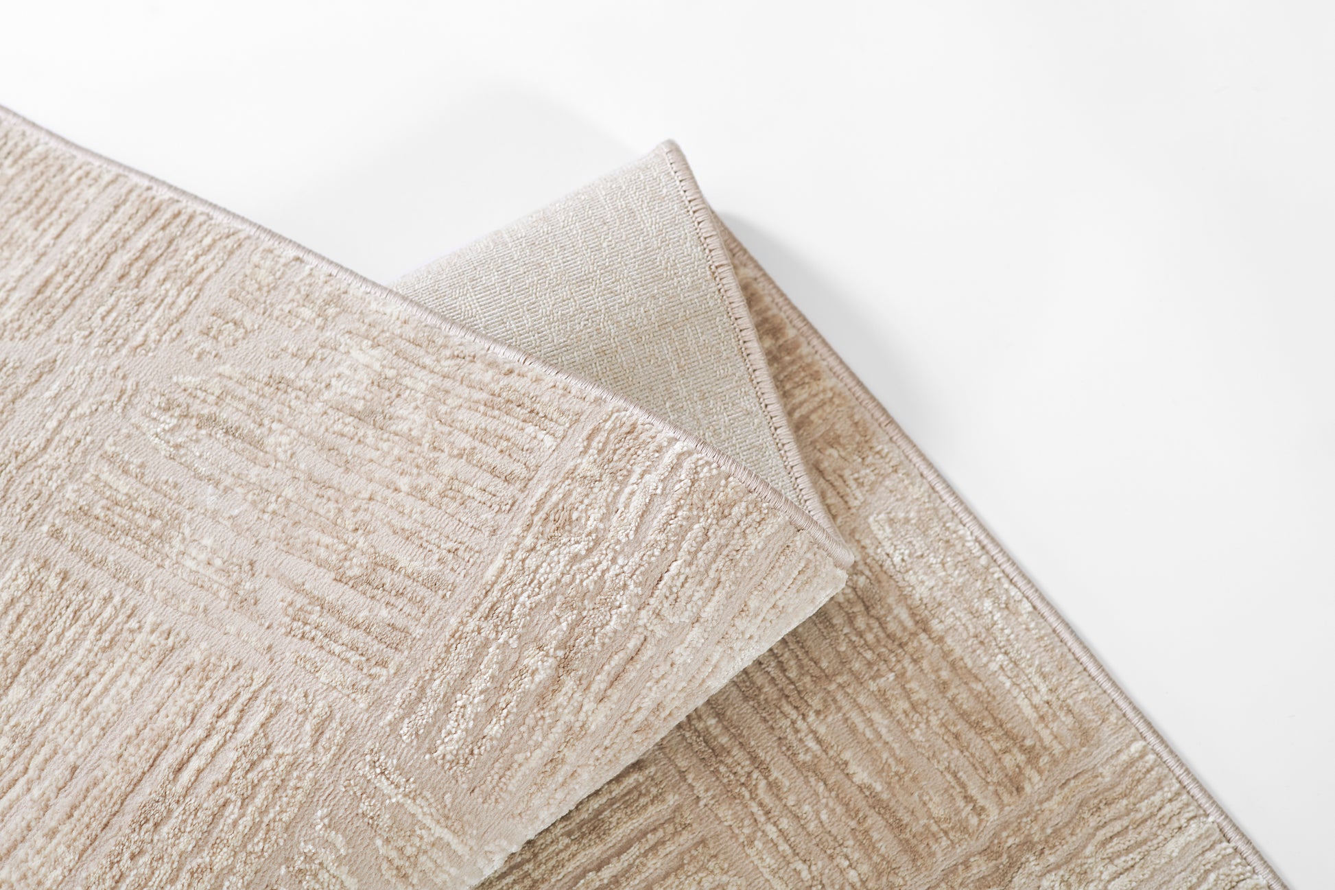 Beige textured rectangular runner with subtle cream linear pattern, soft plush pile & folded corner showing underside.