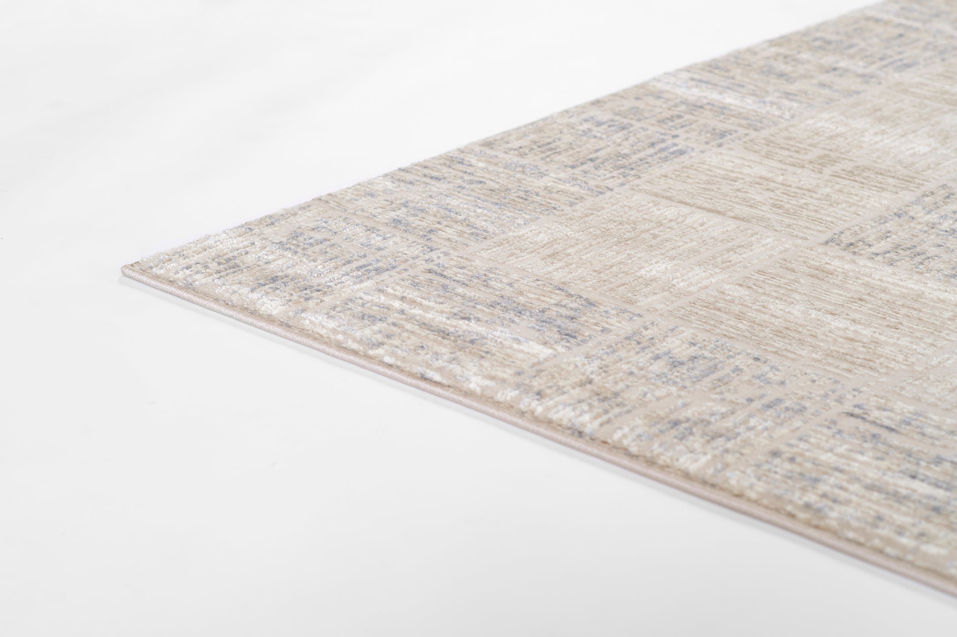 Rectangular beige area rug with pale blue distressed pattern, soft low-pile texture and pink-tinted edge.