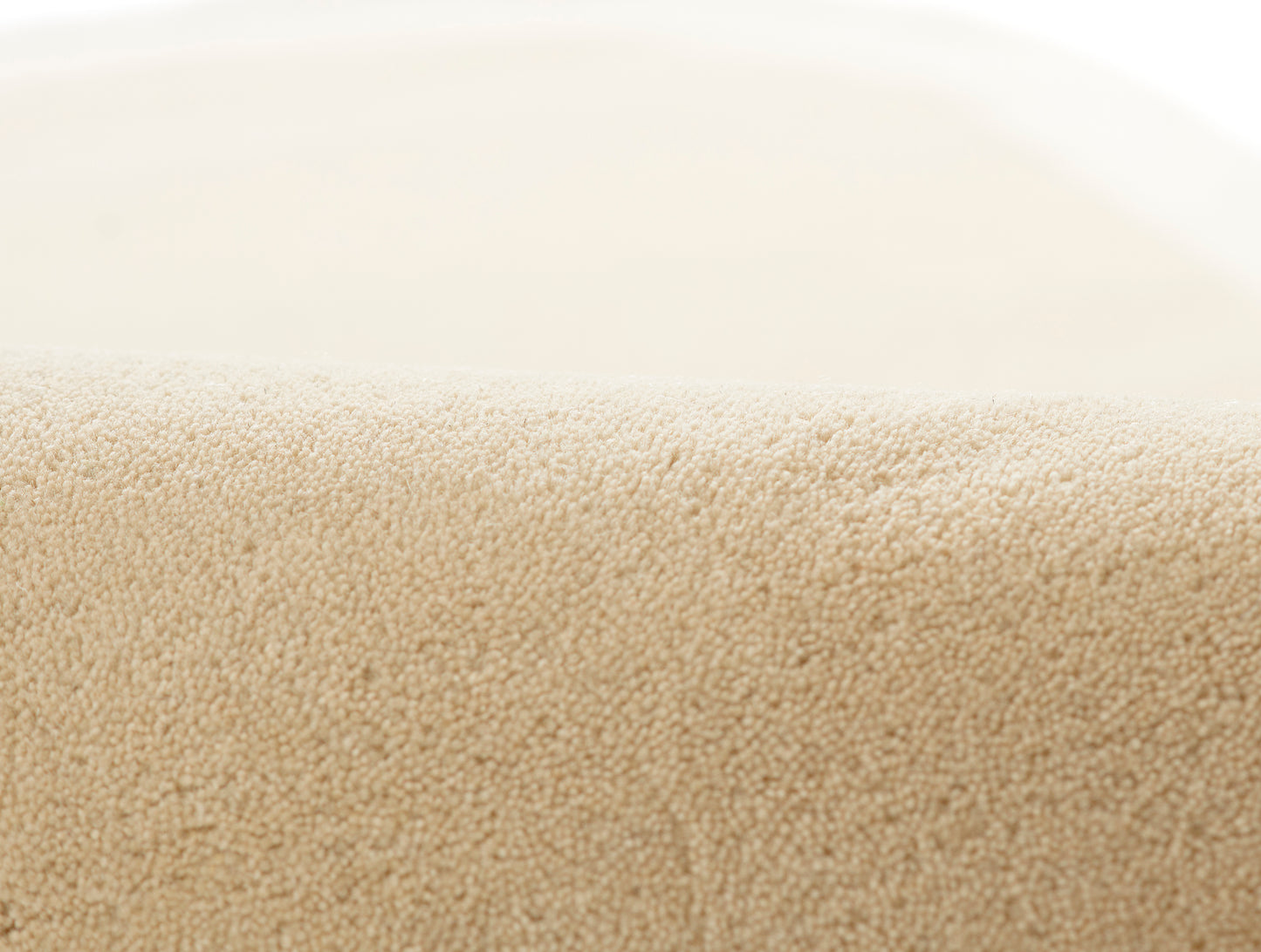 Beige plush rug close-up, soft pile with edge detail, neutral spa-style texture.