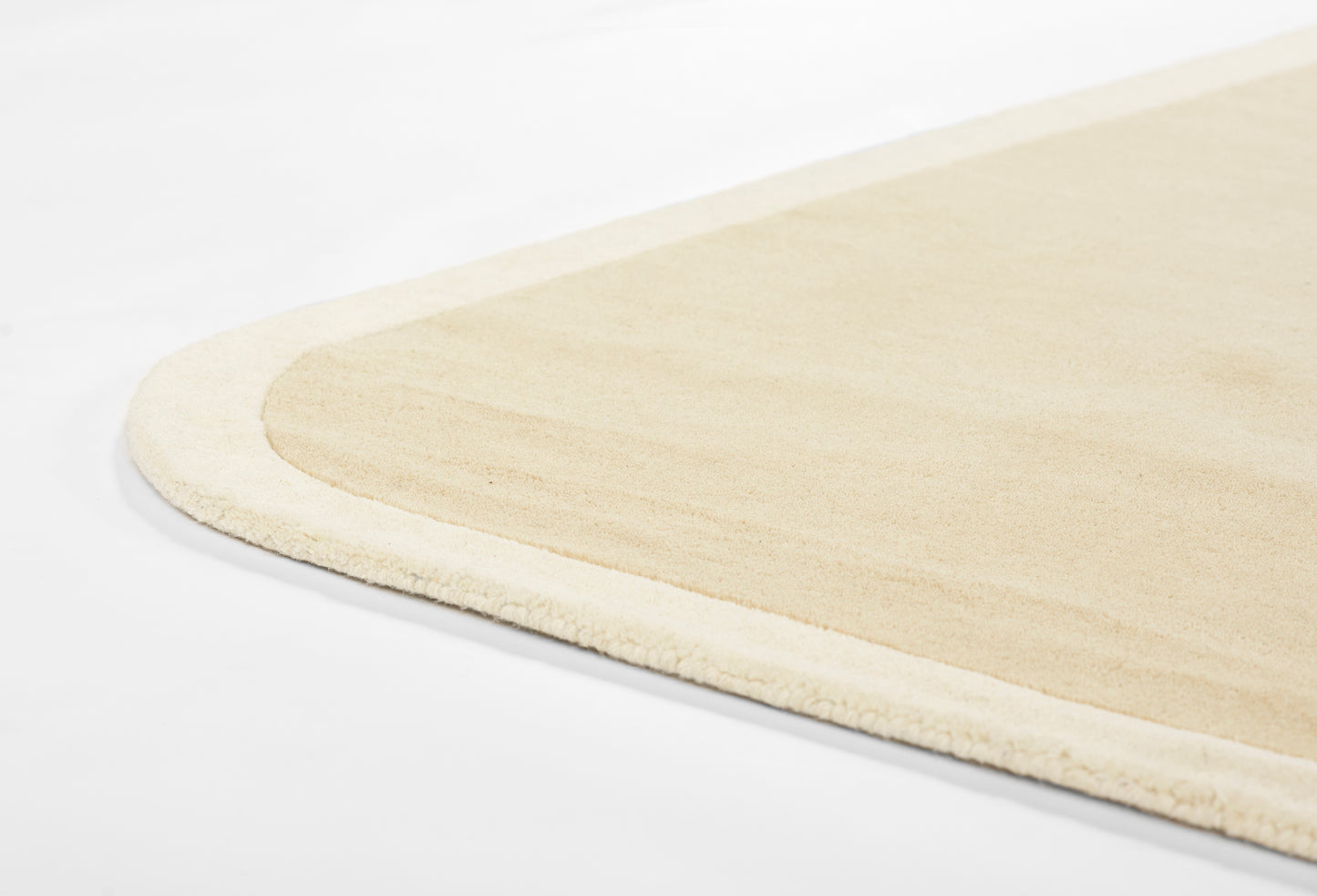 Beige rug with rounded corner, plush border and soft low-pile surface for cozy modern interiors.