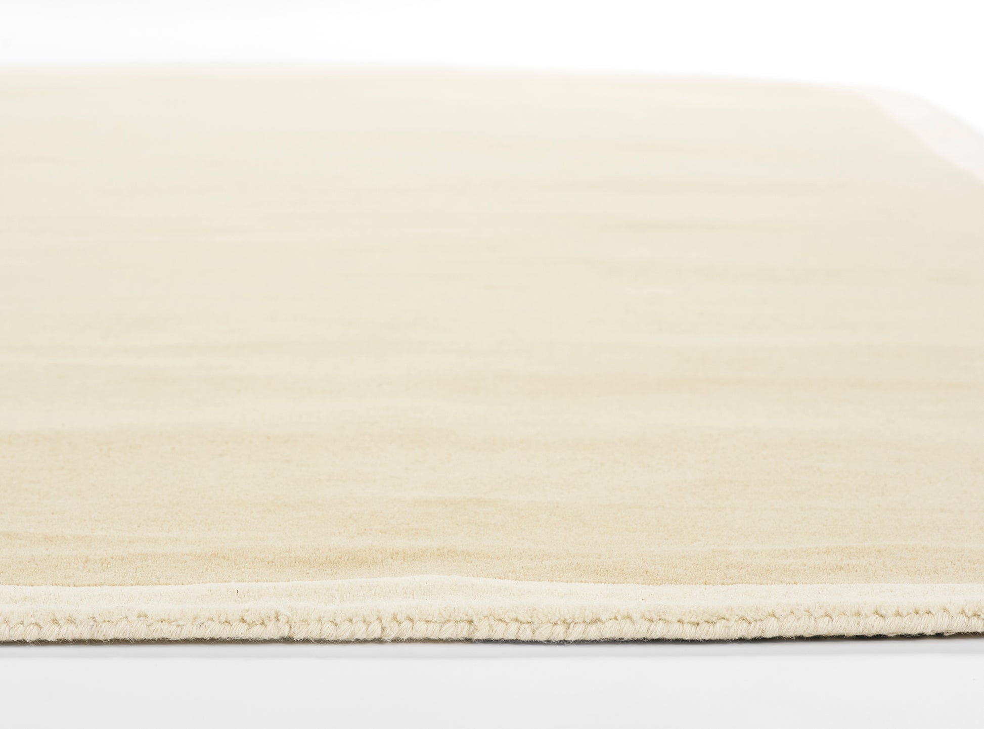 Beige flat-weave rug with short fringe, rectangular shape; warm cream tones for modern living room decor.