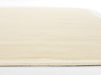 Beige flatweave rug with subtle fringe along the edge; neutral modern decor for living room or bedroom.