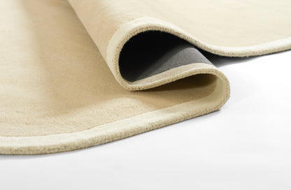 Beige runner rug with light binding, rolled edge revealing gray backing, dense short pile for a neutral living room look.