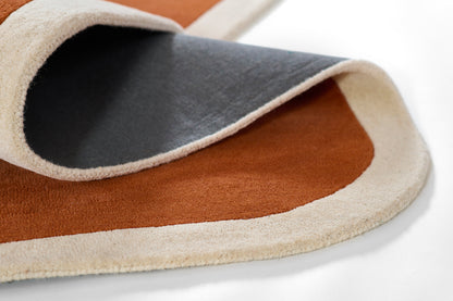 Rust brown and dark gray rug with beige fringe trim; soft pile and rolled edge.