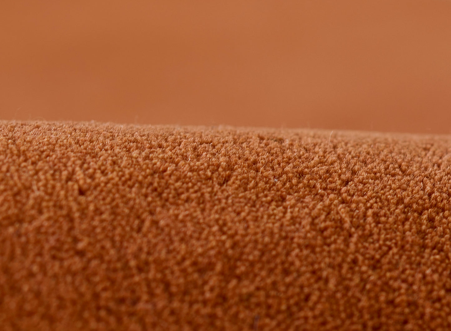 Close-up of orange textured rug pile with tiny loop fibers, warm cozy rug material.