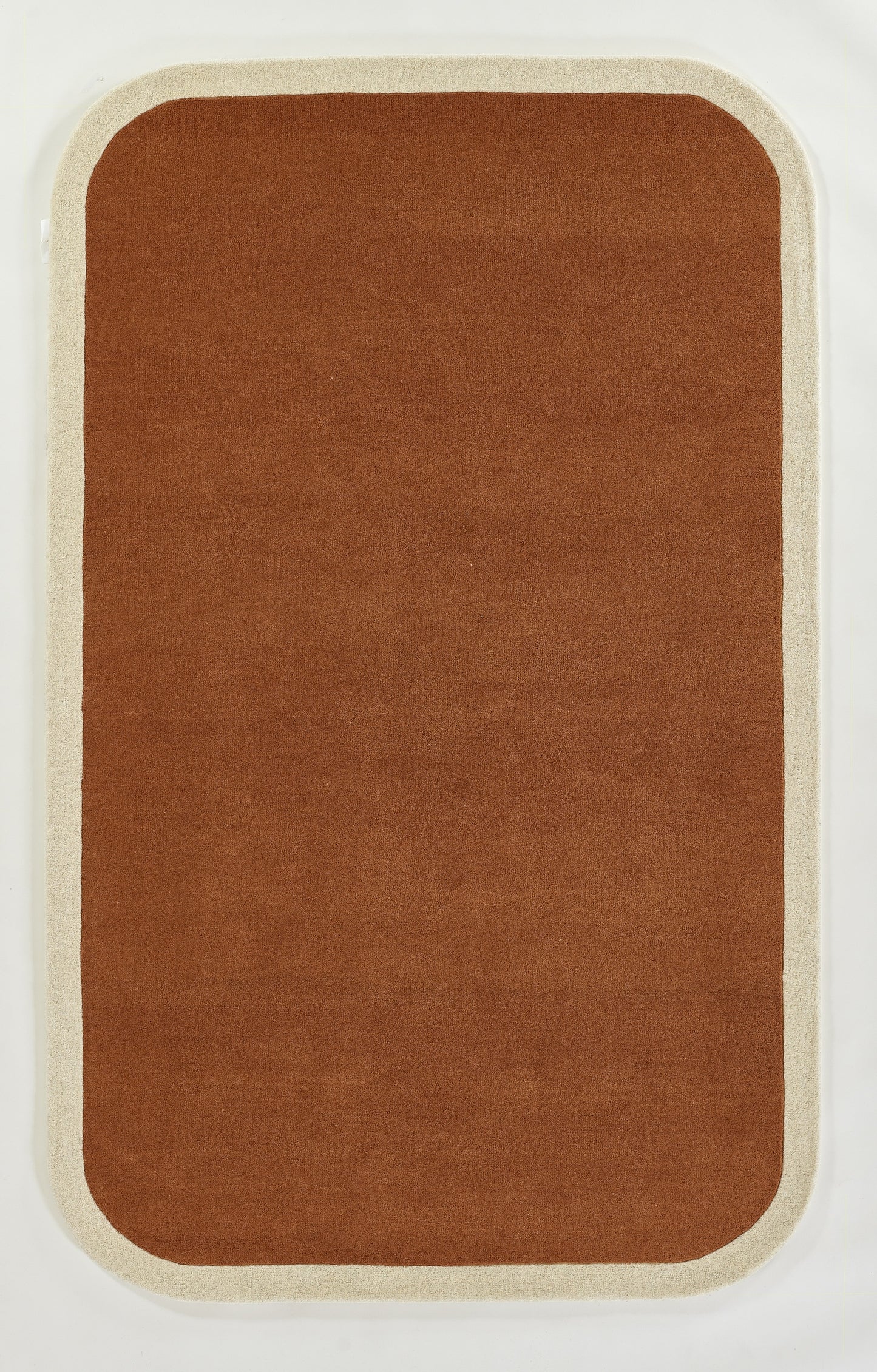 Rectangular rug with rounded corners, burnt orange center and beige border, soft plush texture.