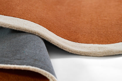 Close-up of tan runner rug with cream binding, folded to reveal gray underside and plush texture.