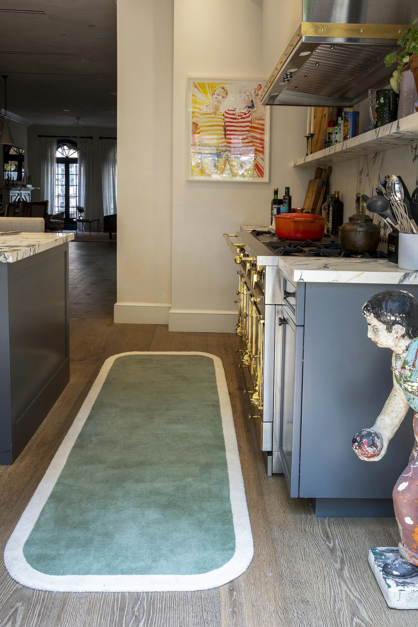 Teal-green rectangular kitchen runner rug with a white border, long and narrow on wood flooring in a modern kitchen.