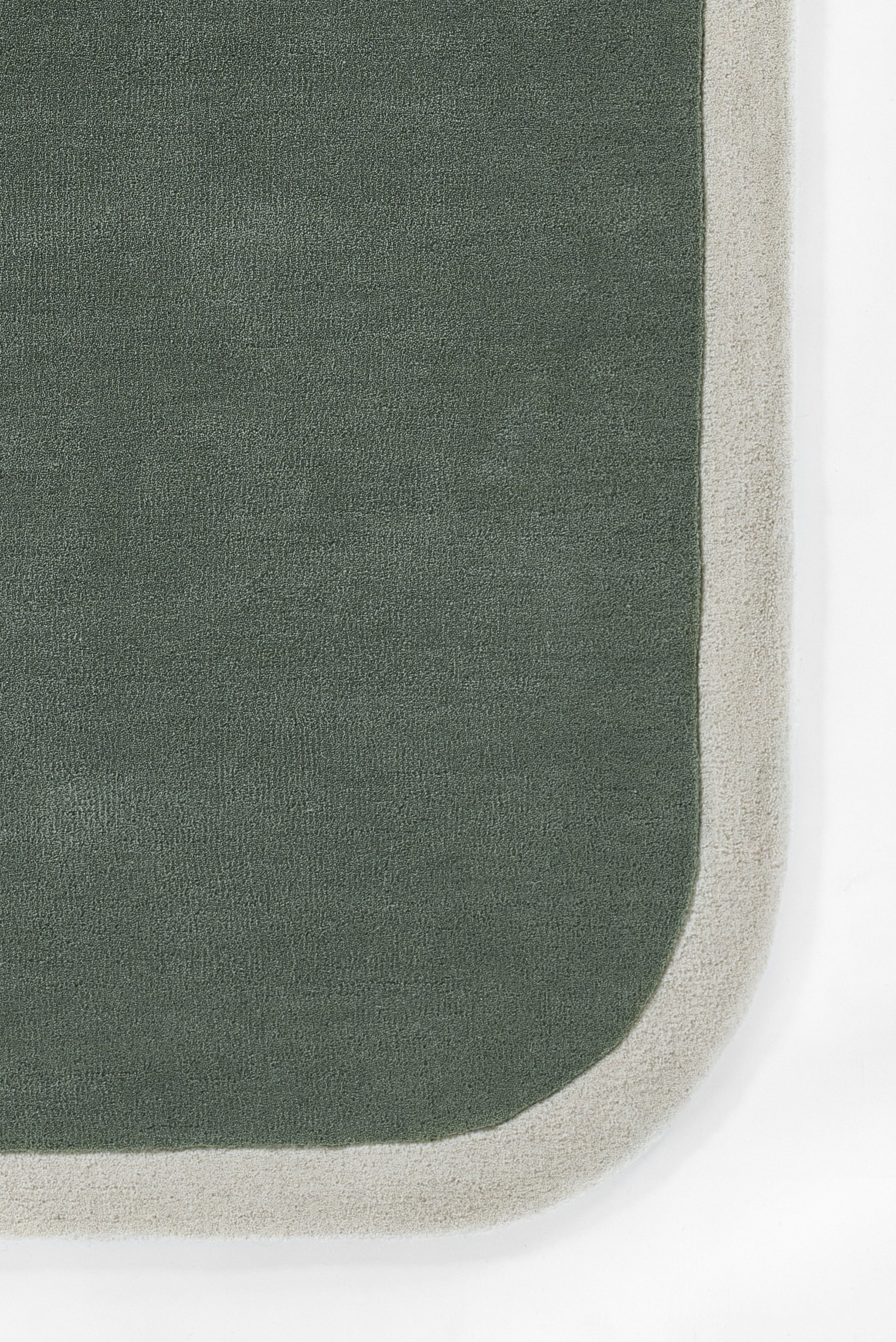 Dark green woven rug with light beige border and rounded corner; modern, casual floor decor.