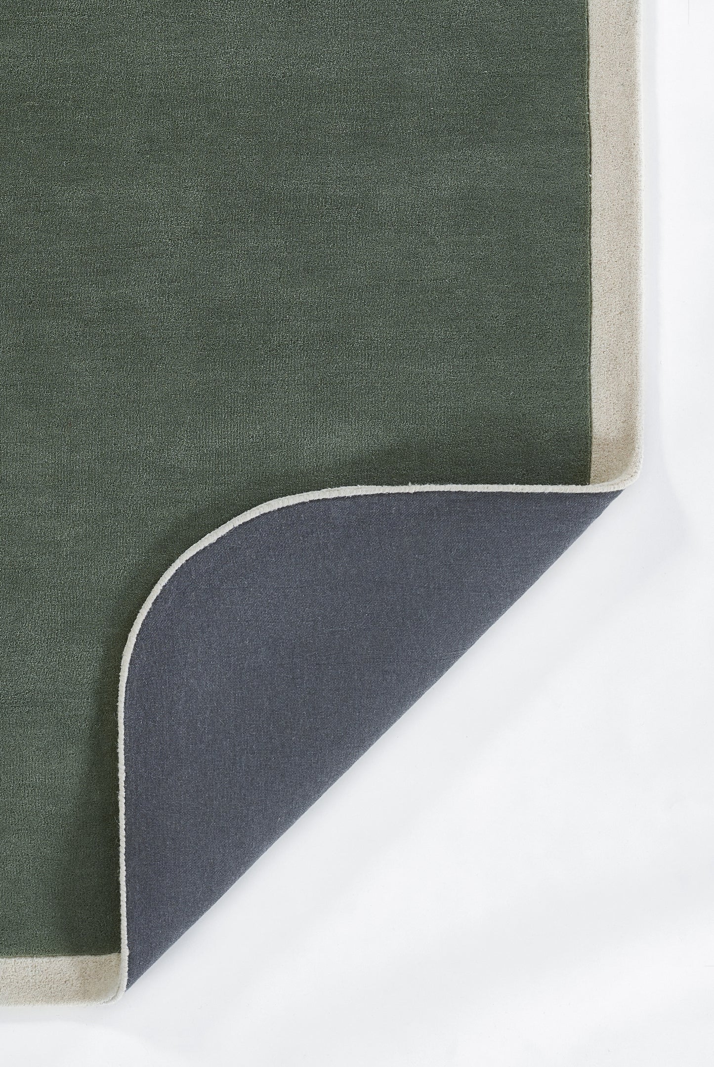 Dark green rectangular rug with beige border, folded corner reveals navy underside; modern indoor rug.