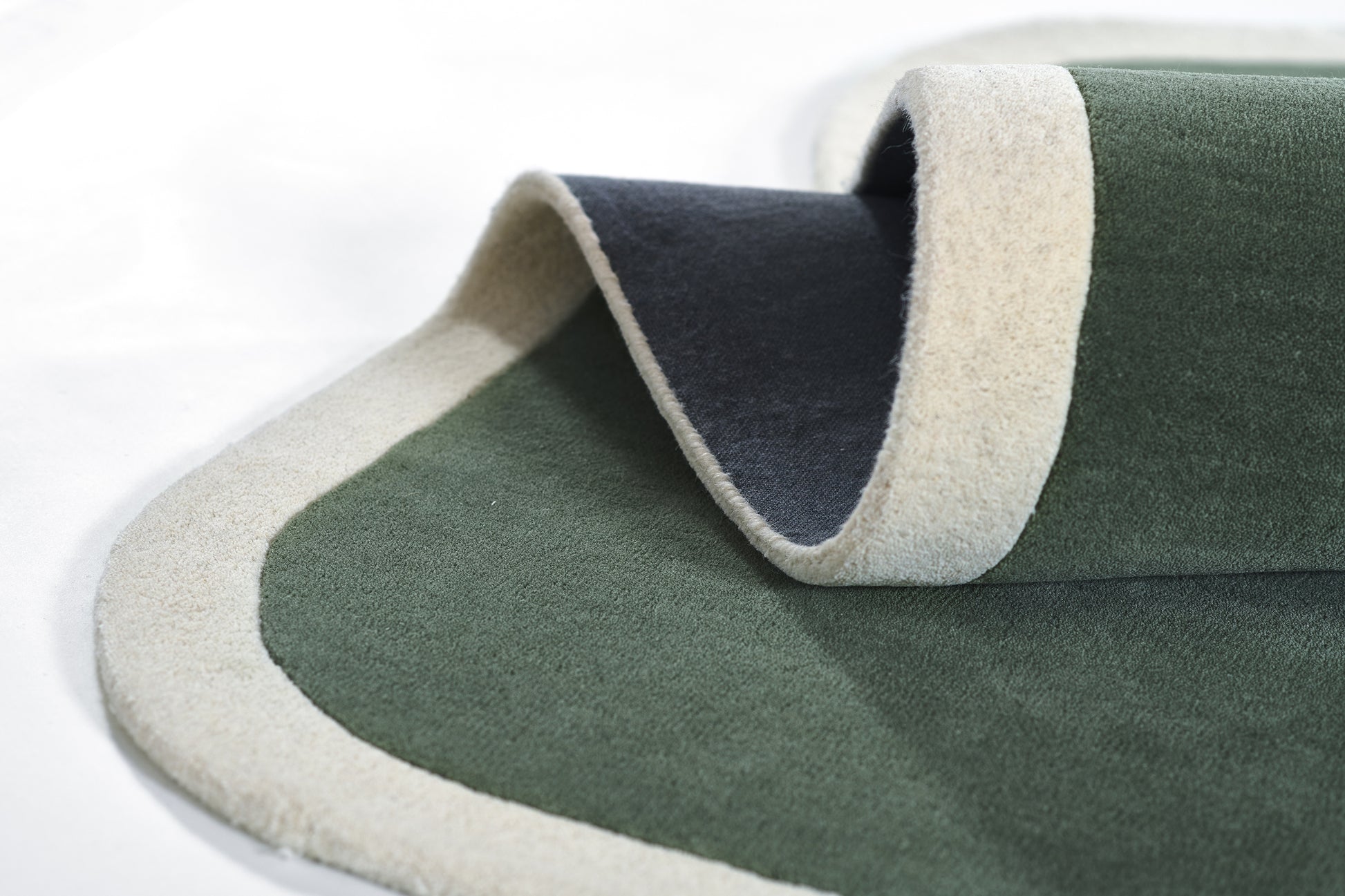 Dark green rug with light beige border, soft pile, rolled edge detail for modern floor decor.