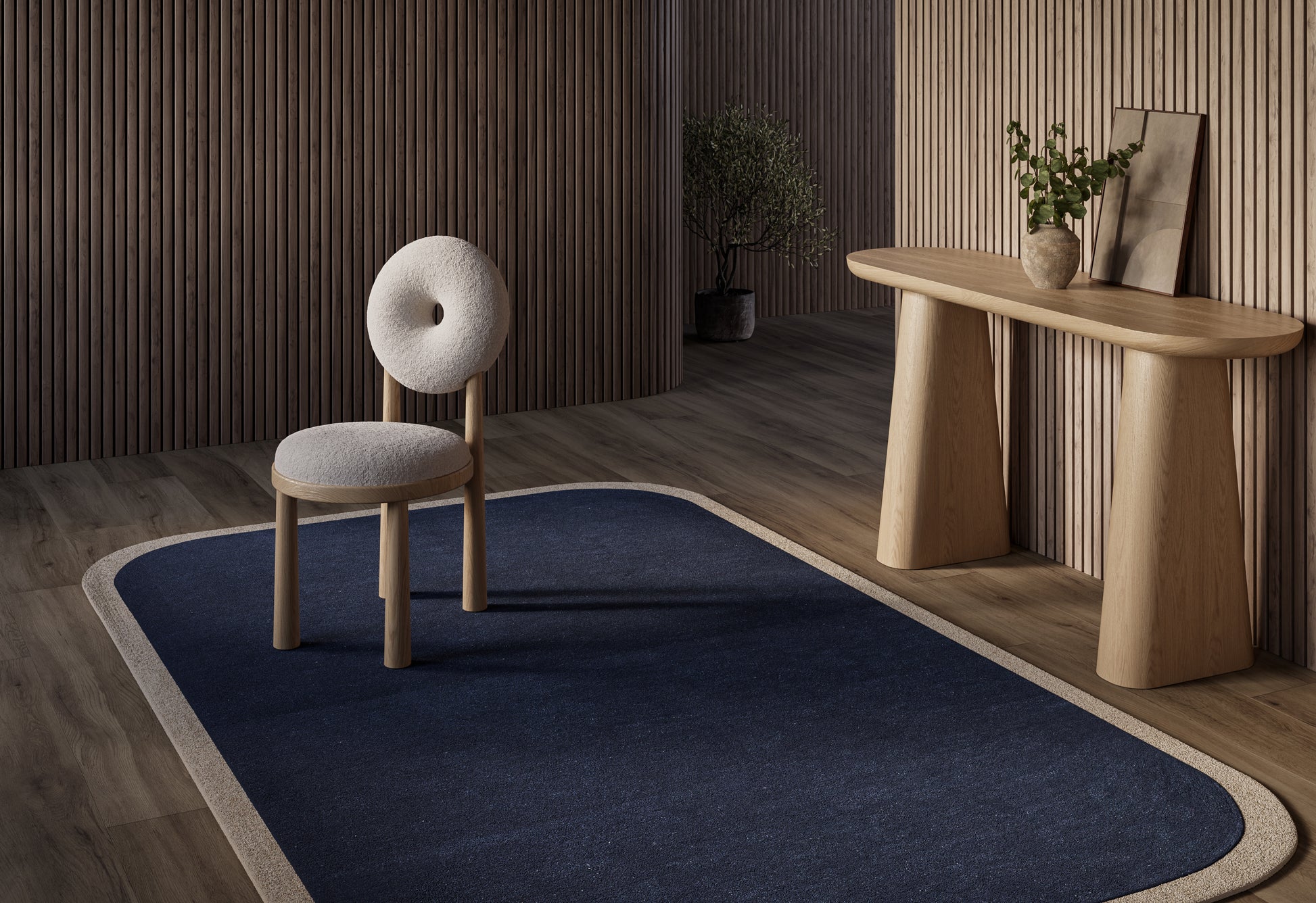 Navy rug with beige border under a light wood chair with round back cushion and curved-leg console table in a warm wooden interior.