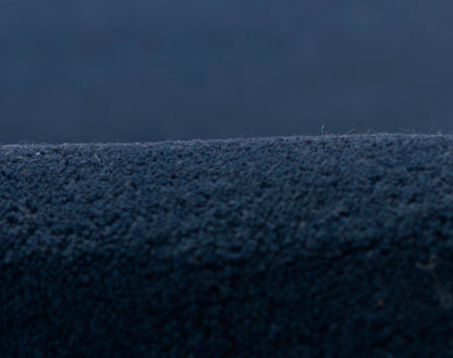 Navy blue textured fabric close-up with dense short pile; plush blanket or upholstery material.