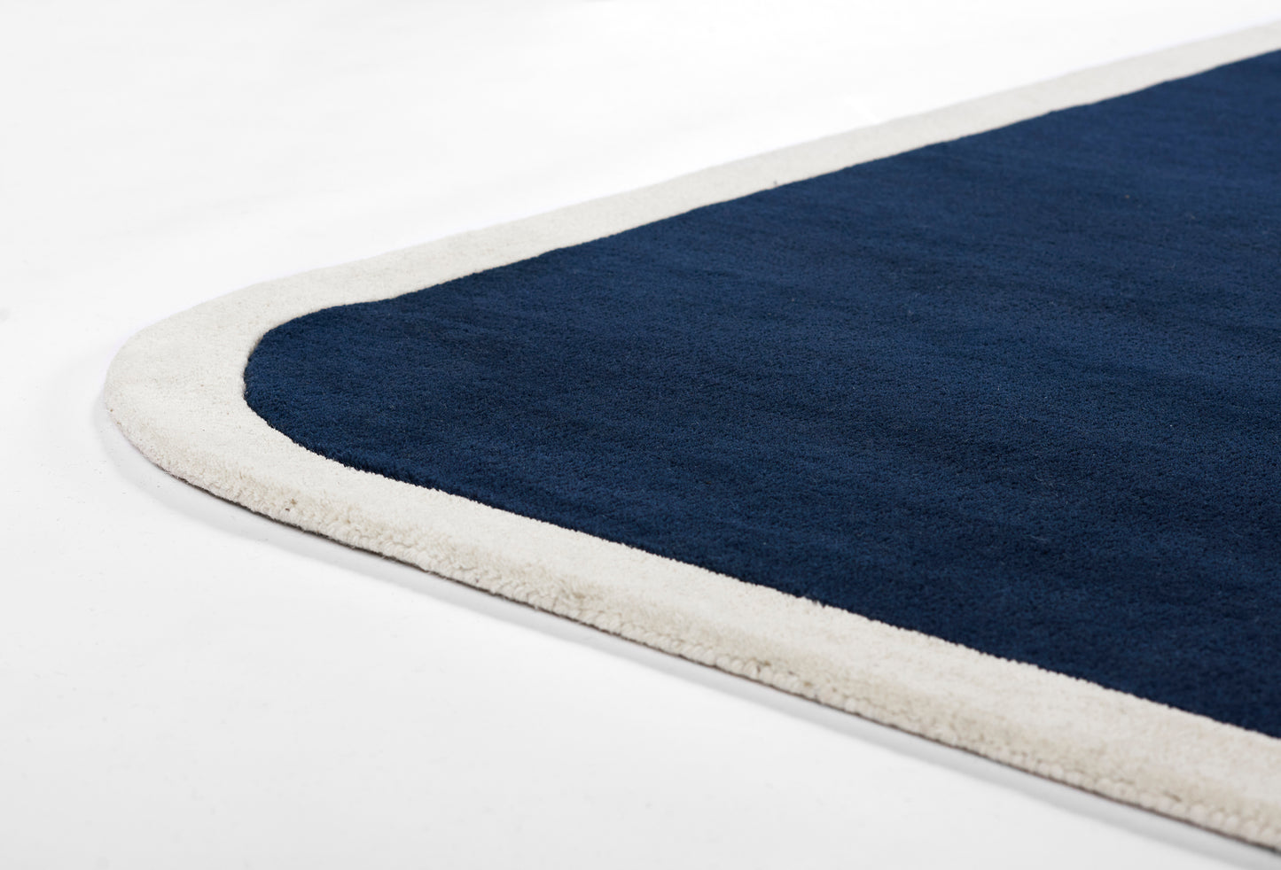 Navy blue rug with a light beige border, rounded corner, modern minimalist style for living room decor.