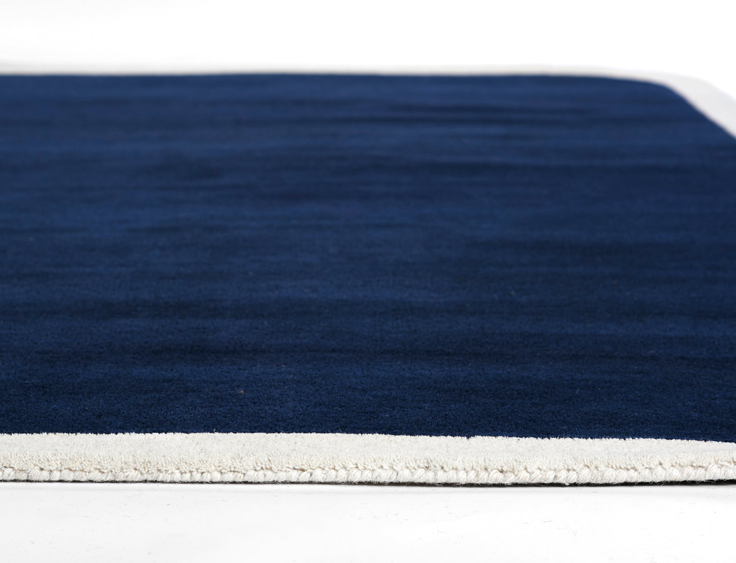 Navy blue rectangular rug with cream fringe along one edge; plush, soft texture.
