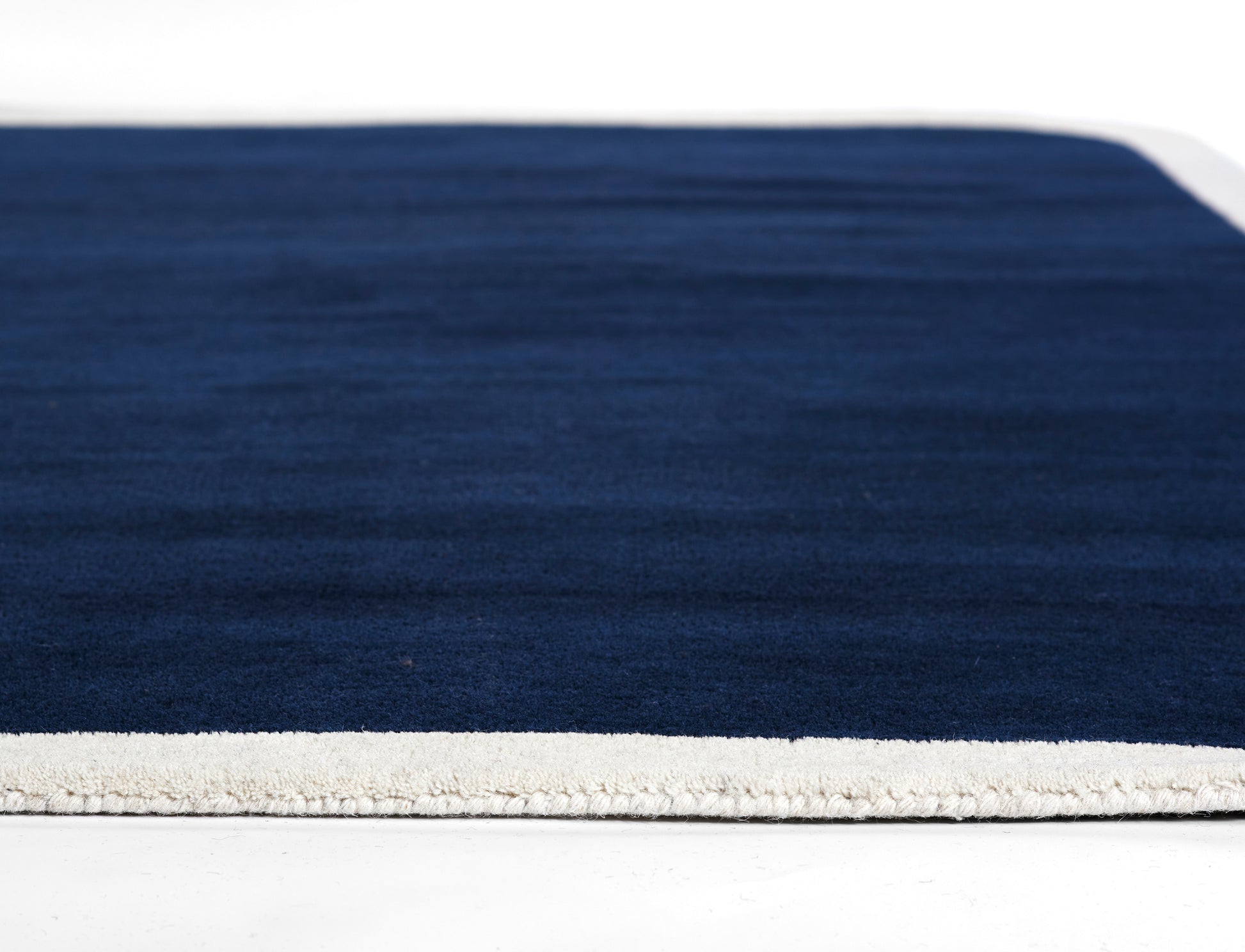 Rectangular navy runner rug with a light cream border along the edge.
